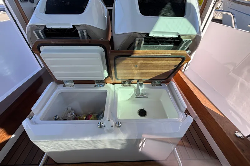Slide: The Image of 2022 Axopar 28 AFT CABIN interior with open storage compartments and sink. - 33