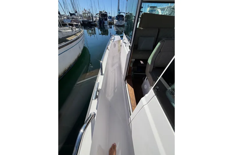 Slide: The Image of 2022 Axopar 28 AFT CABIN boat docked, showing side walkway and interior seating. - 43