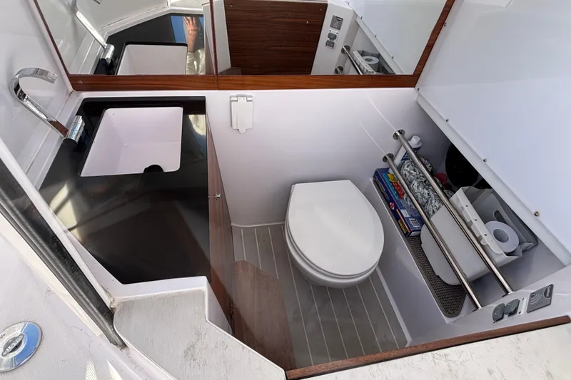 Slide: The Image of 2022 Axopar 28 AFT CABIN bathroom with sink, toilet, and storage shelves. - 47