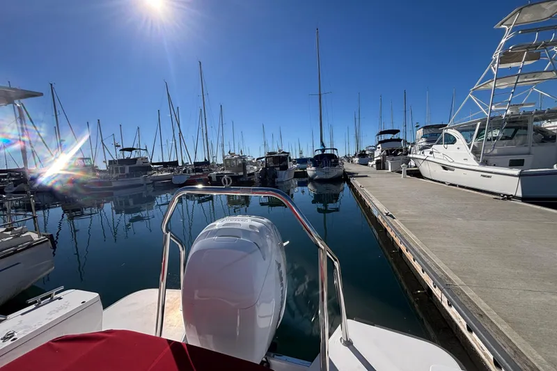 Slide: The Image of 2022 Axopar 28 AFT CABIN docked at a sunny marina with sailboats. - 7