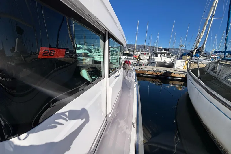 Slide: The Image of 2022 Axopar 28 AFT CABIN docked at marina, reflecting clear blue sky. - 8