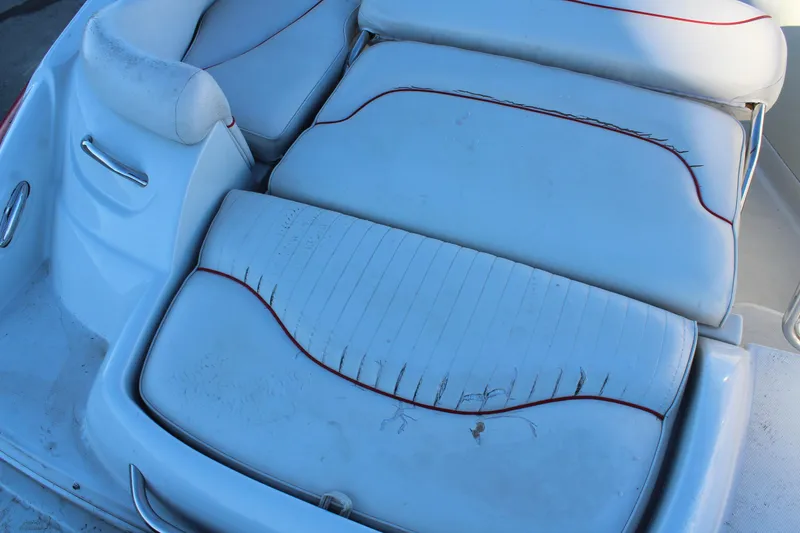 Slide: The Image of 2007 Crownline 240 EX boat interior with worn white upholstery and red accents. - 10