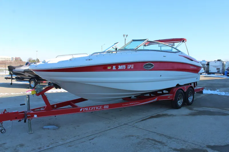 Slide: The Image of 2007 Crownline 240 EX boat on a red trailer, parked outdoors. - 4