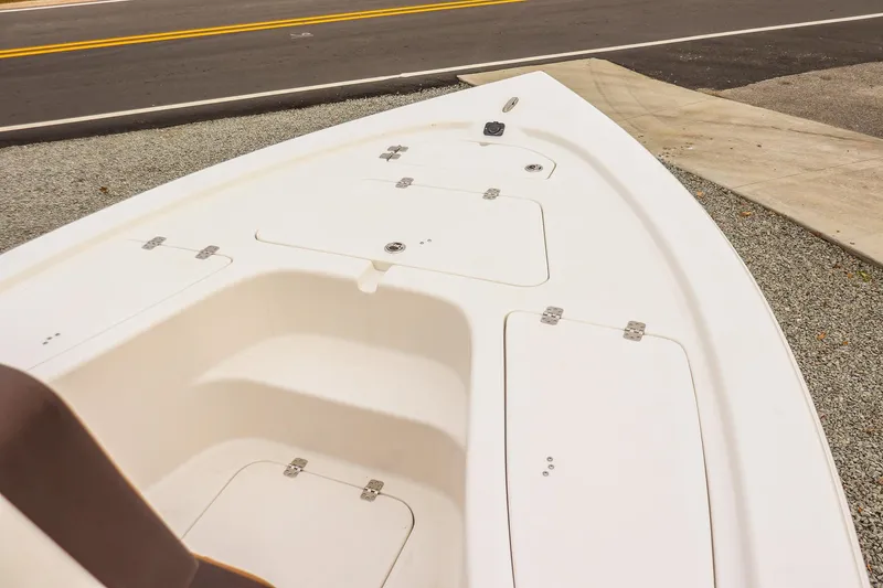 Slide: The Image of 2026 Sea Pro 210 Bay boat deck with storage compartments, parked near a road. - 16