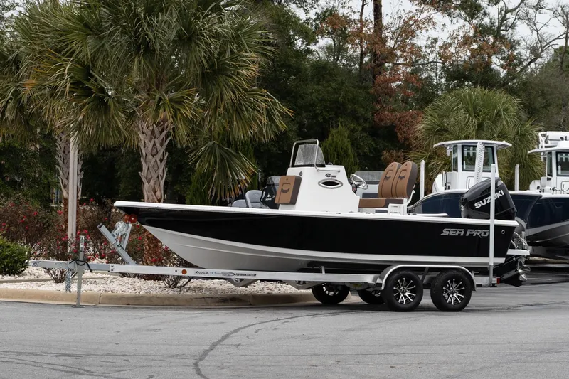 Slide: The Image of 2026 Sea Pro 210 Bay boat on trailer with Suzuki outboard motor, parked outdoors. - 2
