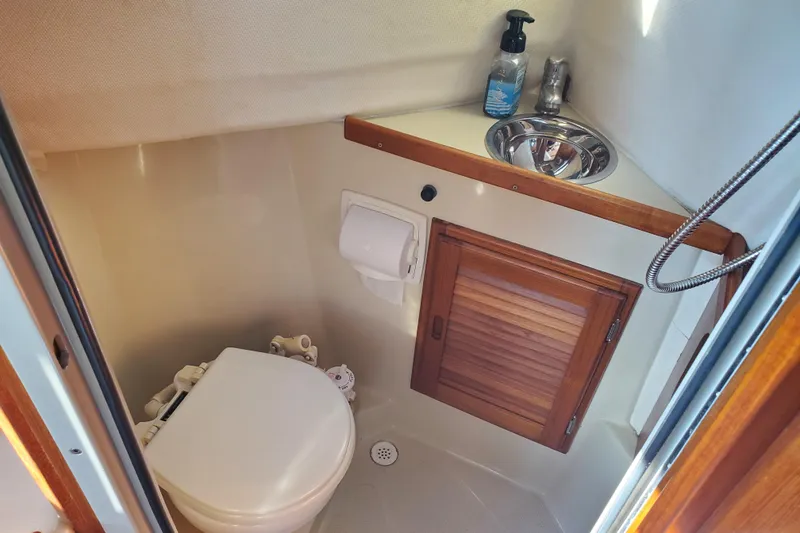 Slide: The Image of Compact bathroom in 2008 Ranger Tugs R-25 boat with toilet, sink, and wooden cabinet. - 20
