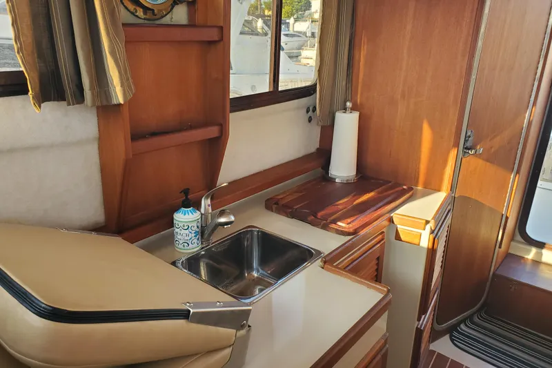 Slide: The Image of 2008 Ranger Tugs R-25 interior kitchen with sink, wooden cabinetry, and window view. - 8