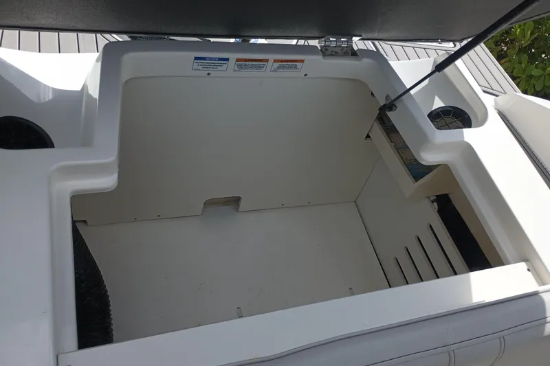 Slide: The Image of 2023 Sea Ray SPX 190 Outboard storage compartment, open and empty, with sunlight casting shadows. - 23