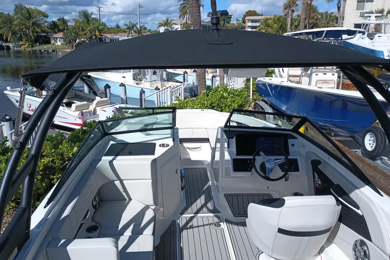 Slide: The Image of 2023 Sea Ray SPX 190 Outboard boat interior with steering wheel and seating, docked near other boats. - 5