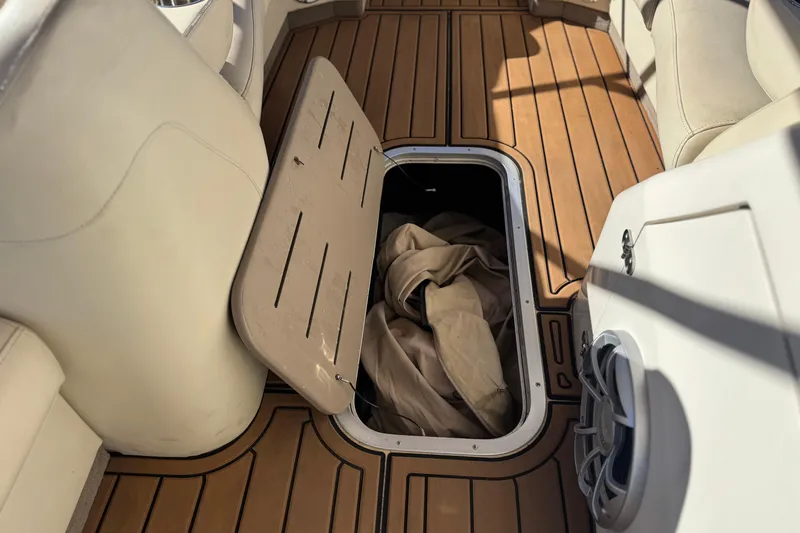 Slide: The Image of 2013 Bennington 2575QCW I/O boat interior with open storage compartment on wooden deck. - 18
