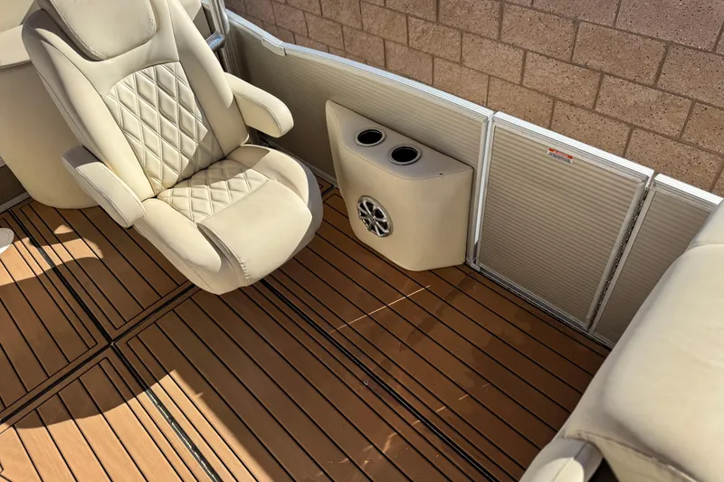 Slide: The Image of 2013 Bennington 2575QCW I/O boat interior with beige seating and wood-style flooring. - 21