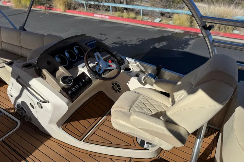 Slide: The Image of 2013 Bennington 2575QCW I/O boat interior with steering wheel and beige seating. - 31