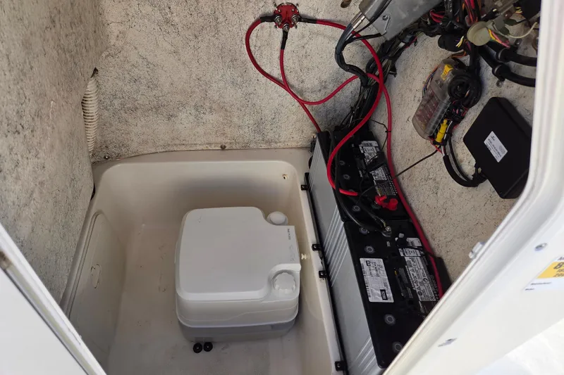 Slide: The Image of 2015 Key West 203 FS boat battery compartment with wiring and portable toilet. - 15