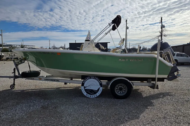 Slide: The Image of 2015 Key West 203 FS boat on trailer, green hull, parked outdoors under cloudy sky. - 2