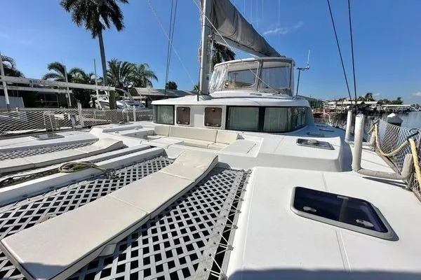 Slide: The Image of 2006 Lagoon 440 catamaran with spacious deck, docked in a sunny marina setting. - 13