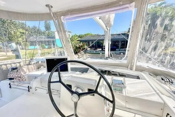 Slide: The Image of Helm of 2006 Lagoon 440 catamaran with clear canopy and lush surroundings. - 18