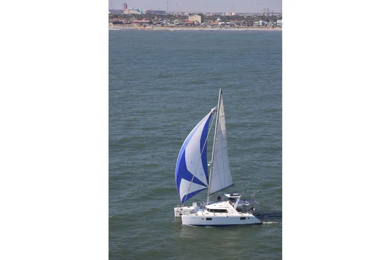 Slide: The Image of Sailing Lagoon 440 catamaran from 2006 with blue and white sails on open water. - 2