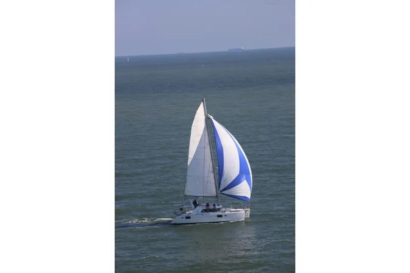 Slide: The Image of 2006 Lagoon 440 catamaran sailing on open sea with blue and white spinnaker. - 3