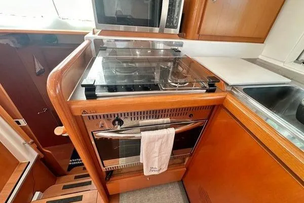 Slide: The Image of 2006 Lagoon 440 yacht kitchen with stove, oven, and microwave in wooden cabinetry. - 30