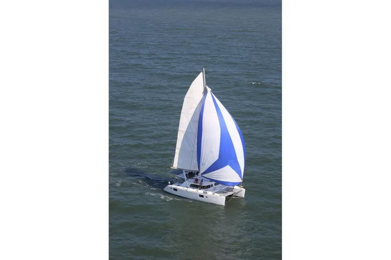 Slide: The Image of 2006 Lagoon 440 catamaran sailing with blue and white spinnaker on open water. - 4