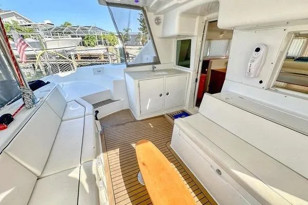 Slide: The Image of 2006 Lagoon 440 yacht interior with white seating, wooden flooring, and compact kitchenette. - 48