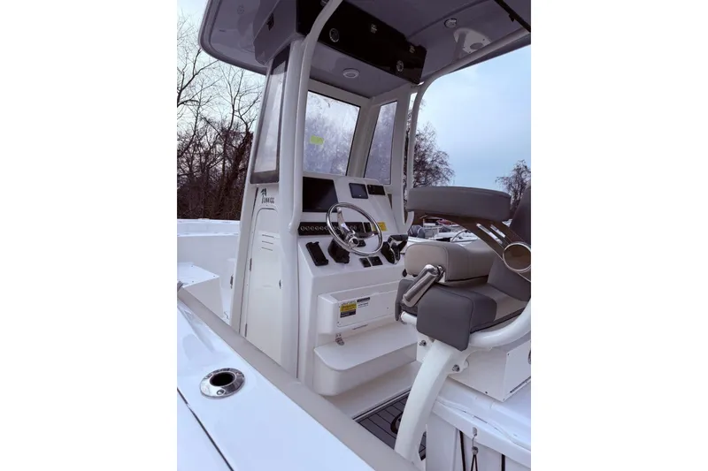 Slide: The Image of 2026 Key West 244 Center Console boat interior with seating and storage, near a large warehouse. - 3