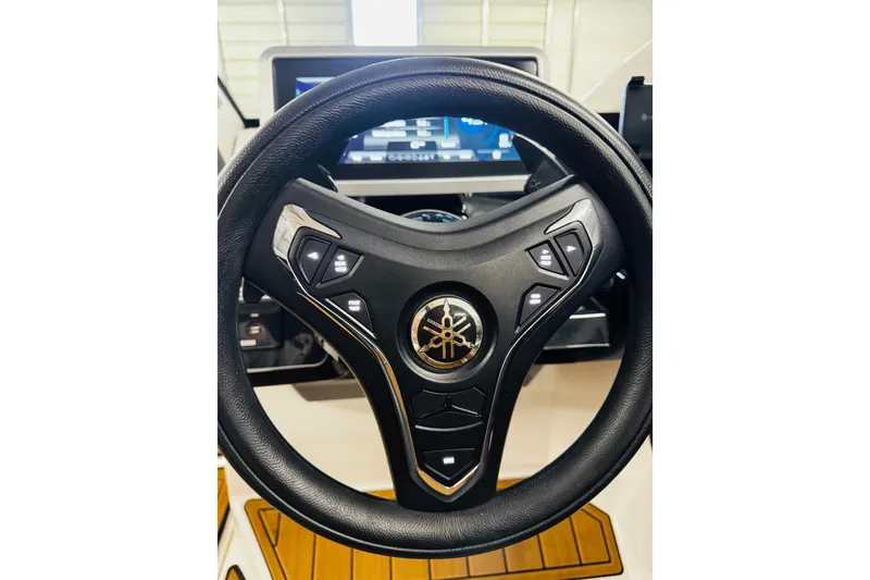 Slide: The Image of Steering wheel of 2024 Yamaha Boats 275SD, featuring control buttons and logo. - 11