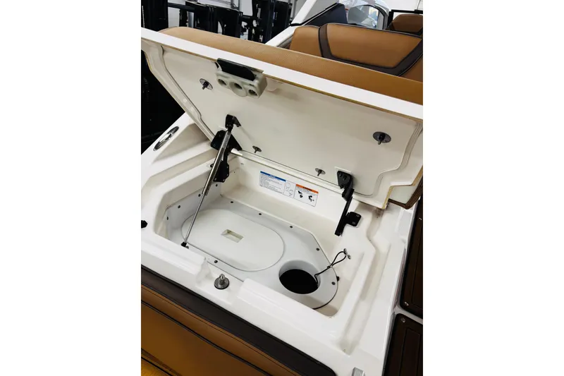 Slide: The Image of Open storage compartment in 2024 Yamaha Boats 275SD, featuring brown seating and white interior. - 21