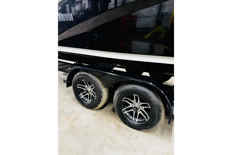Slide: The Image of 2024 Yamaha Boats 275SD trailer with dual wheels, black finish, and stylish rims. - 31