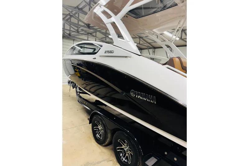 Slide: The Image of 2024 Yamaha Boats 275SD, sleek black and white design, on trailer in a garage. - 5