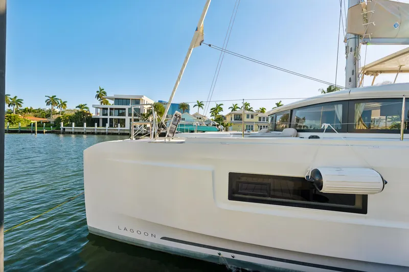 Slide: The Image of 2022 Lagoon 46 yacht docked by waterfront homes, sunny day. - 10