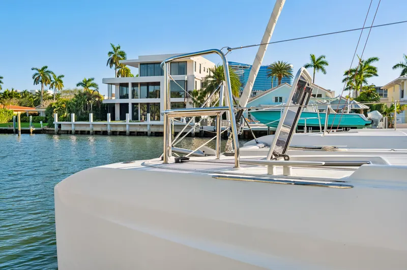 Slide: The Image of Lagoon 46 catamaran docked by waterfront homes, palm trees, and clear blue sky. - 11
