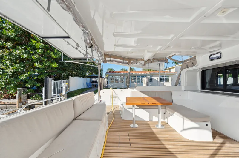 Slide: The Image of Spacious deck of 2022 Lagoon 46 catamaran with seating and table, surrounded by greenery. - 18