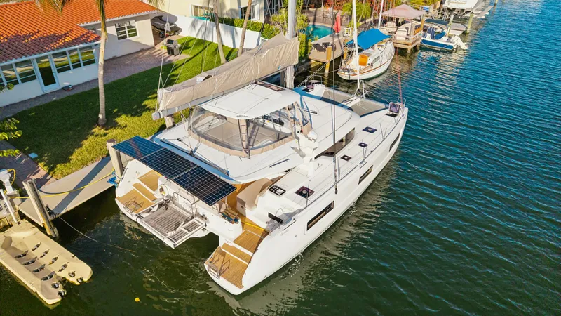 Slide: The Image of 2022 Lagoon 46 catamaran docked in a sunny marina, featuring solar panels and spacious deck. - 3