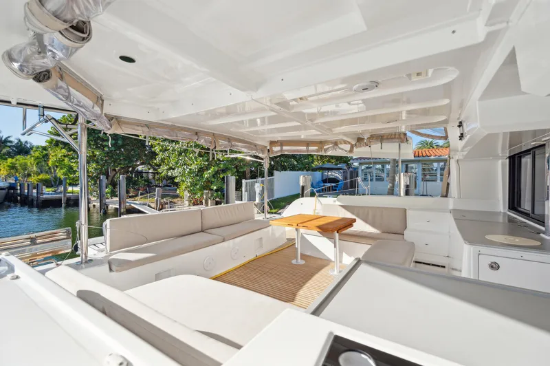 Slide: The Image of 2022 Lagoon 46 yacht interior with spacious seating and table, docked by lush greenery. - 30