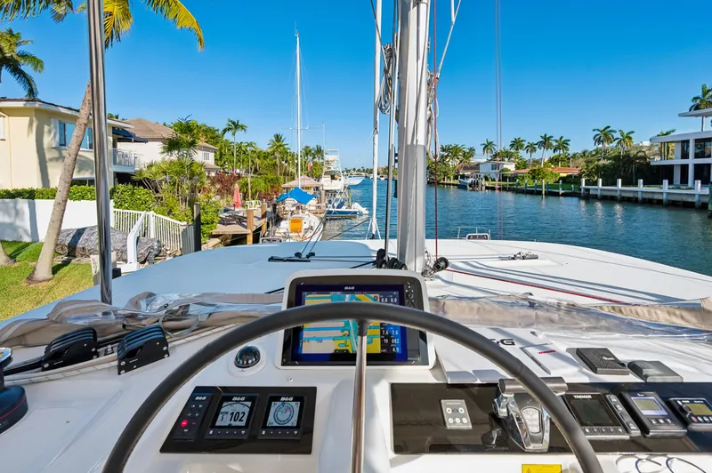 Slide: The Image of Lagoon 46 catamaran cockpit view, 2022 model, navigating a scenic canal with palm trees. - 36