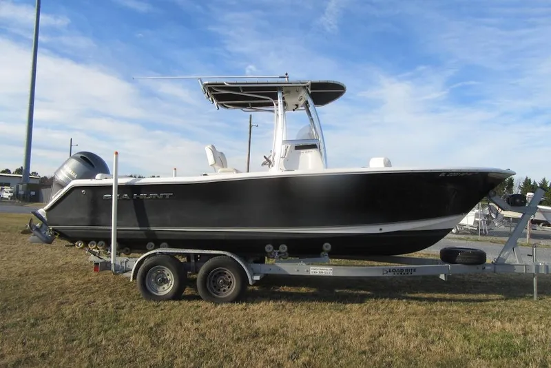 Slide: The Image of 2014 Sea Hunt Ultra 234 boat on trailer, parked on grass under blue sky. - 2