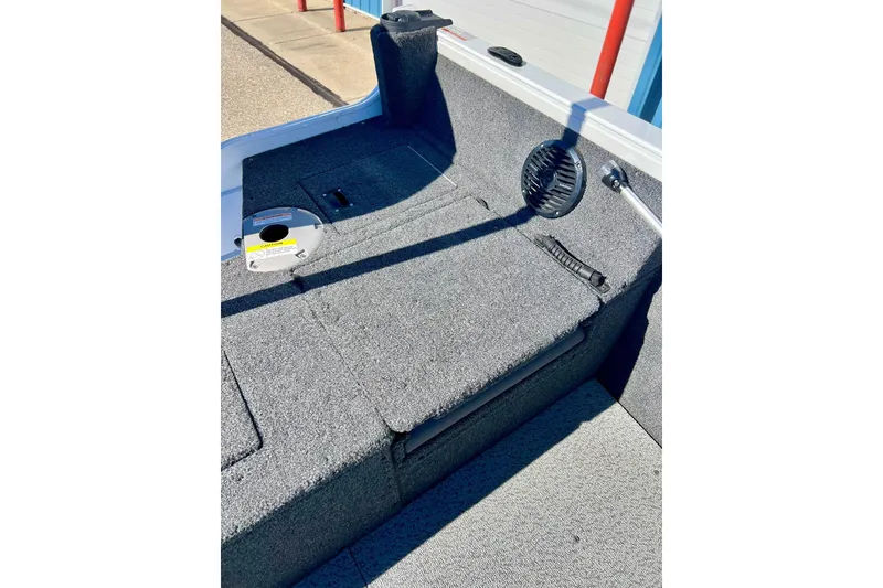 Slide: The Image of 2024 Crestliner 1650 Fish Hawk SC interior with carpeted deck and storage compartments. - 16