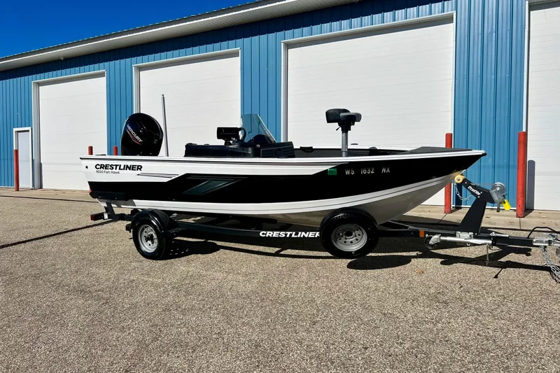 Slide: The Image of 2024 Crestliner 1650 Fish Hawk SC boat on trailer, parked outside blue building. - 3