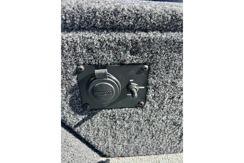 Slide: The Image of 2024 Crestliner 1650 Fish Hawk SC boat trim switch and power outlet on carpeted panel. - 46