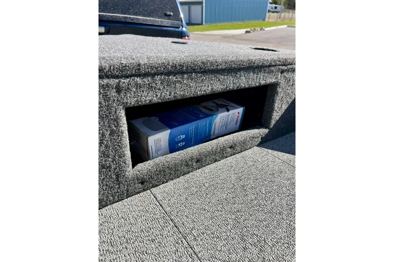 Slide: The Image of 2024 Crestliner 1650 Fish Hawk SC storage compartment with a box inside, outdoor setting. - 50