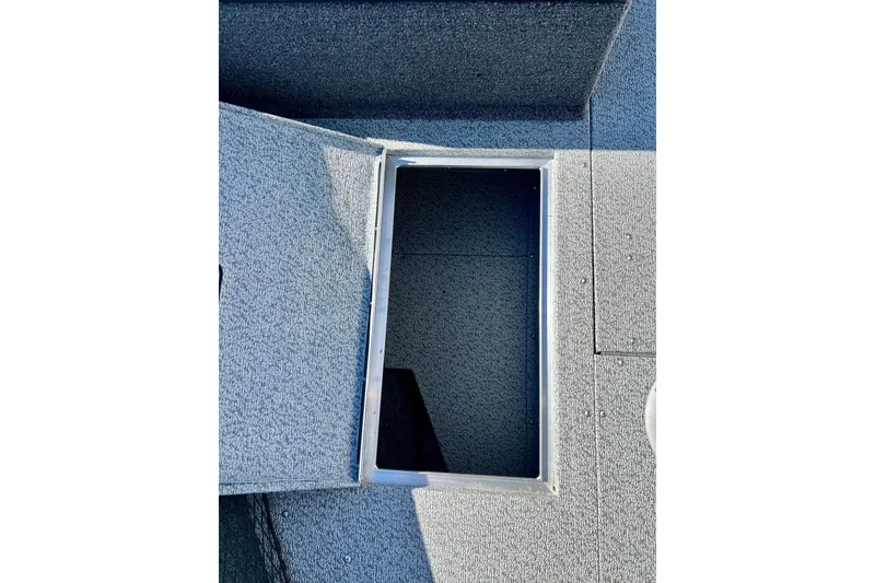 Slide: The Image of 2024 Crestliner 1650 Fish Hawk SC boat storage compartment, open and carpeted. - 53