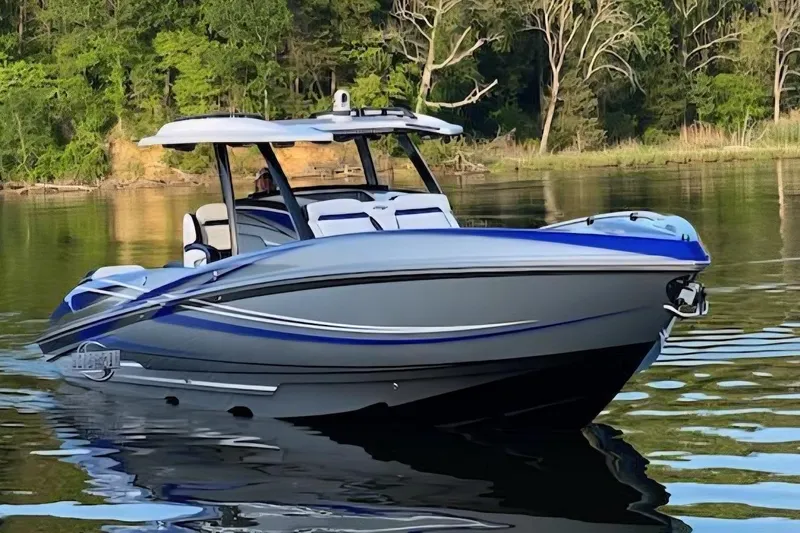 The Image of 2021 Sunsation 34 CCX boat on calm water, surrounded by lush greenery. - 0