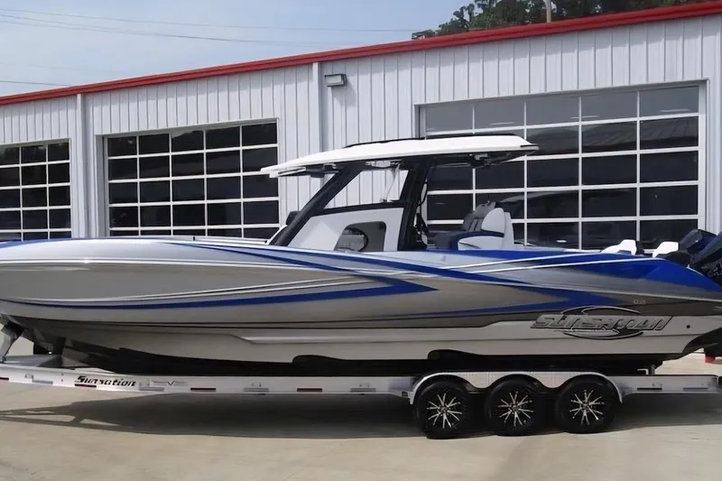 Slide: The Image of 2021 Sunsation 34 CCX boat with sleek design on a trailer outside a garage. - 2