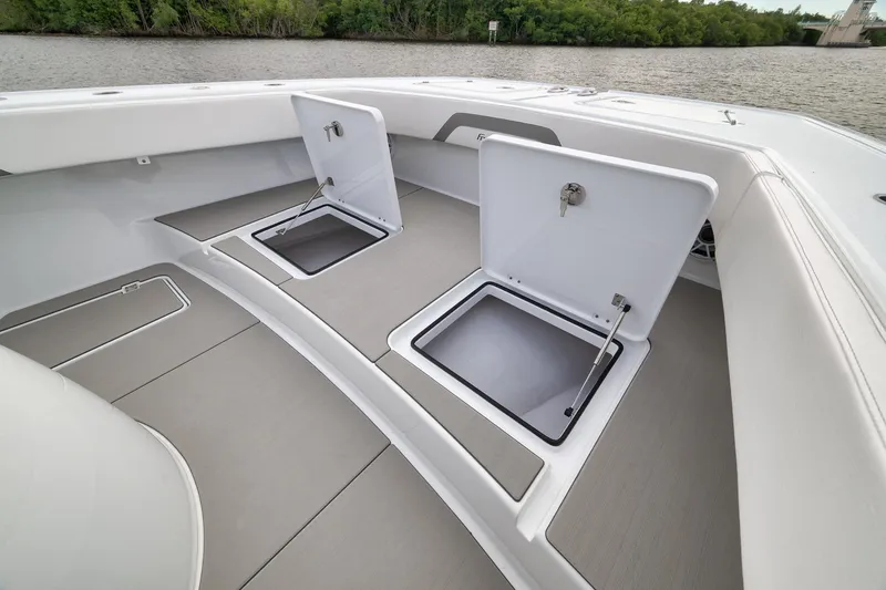 Slide: The Image of Freeman 42LR 2022 boat deck with open storage compartments, near water and greenery. - 74