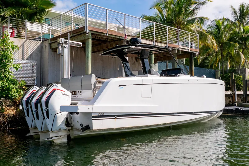 Slide: The Image of 2024 Pardo Yachts 38 docked, featuring triple outboard engines, surrounded by tropical greenery. - 2