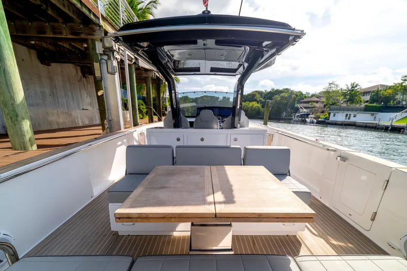 Slide: The Image of 2024 Pardo Yachts 38 interior with seating and table, docked by a scenic waterfront. - 20