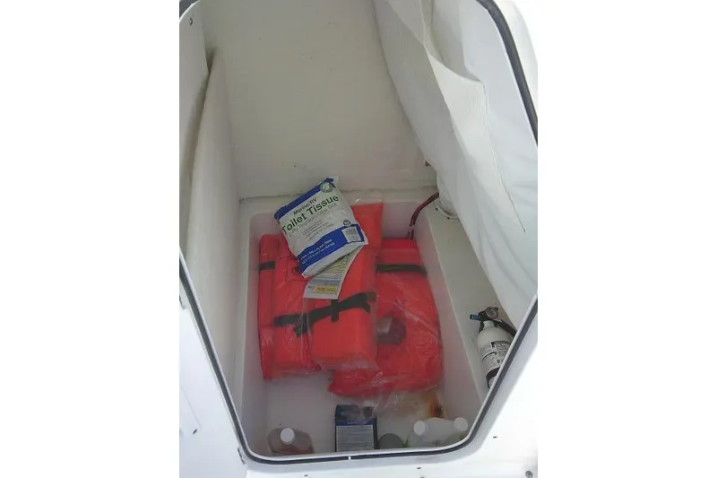 Slide: The Image of Storage compartment in 2023 Sea Hunt Ultra 234 with life jackets and supplies. - 23