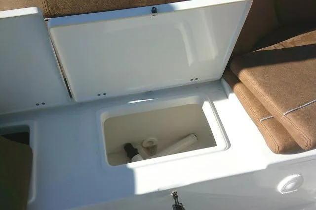 Slide: The Image of 2023 Sea Hunt Ultra 234 boat storage compartment with open lid and brown seating. - 30