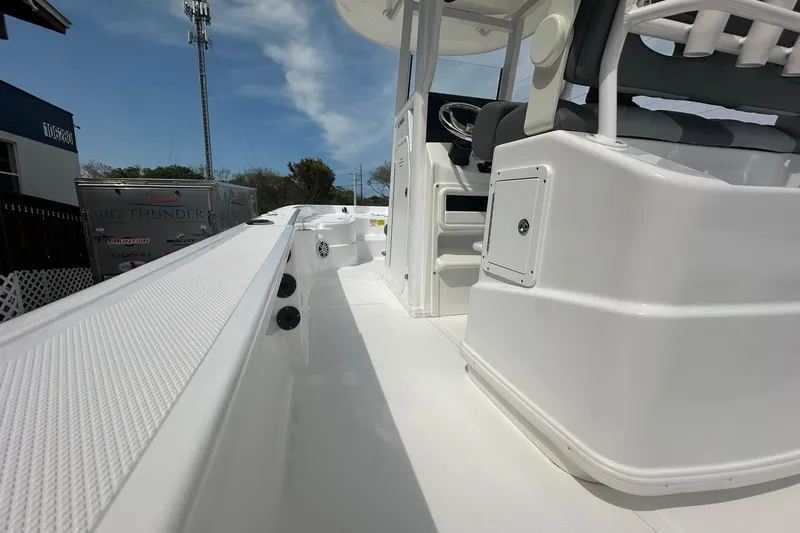 Slide: The Image of 2024 NauticStar 274 Bay boat interior with seating and console, under clear sky. - 6